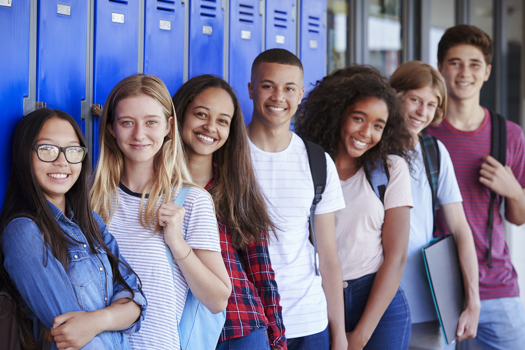 Teenage school kids smiling to camera in school corridor